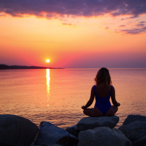femme au bord de l'eau en train de méditer devant un coucher de soleil